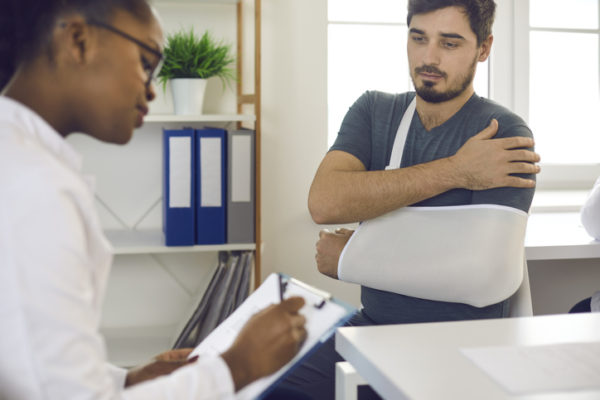 Doctor treating patient in a sling for a shoulder injury 